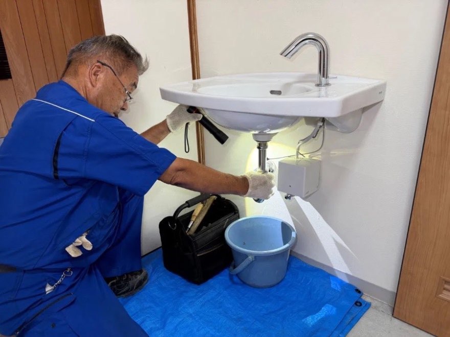 洗面台の下で作業するスタッフ